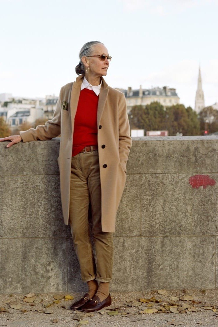 Effortlessly chic fall outfit for women over 60: camel coat over red sweater and tan trousers