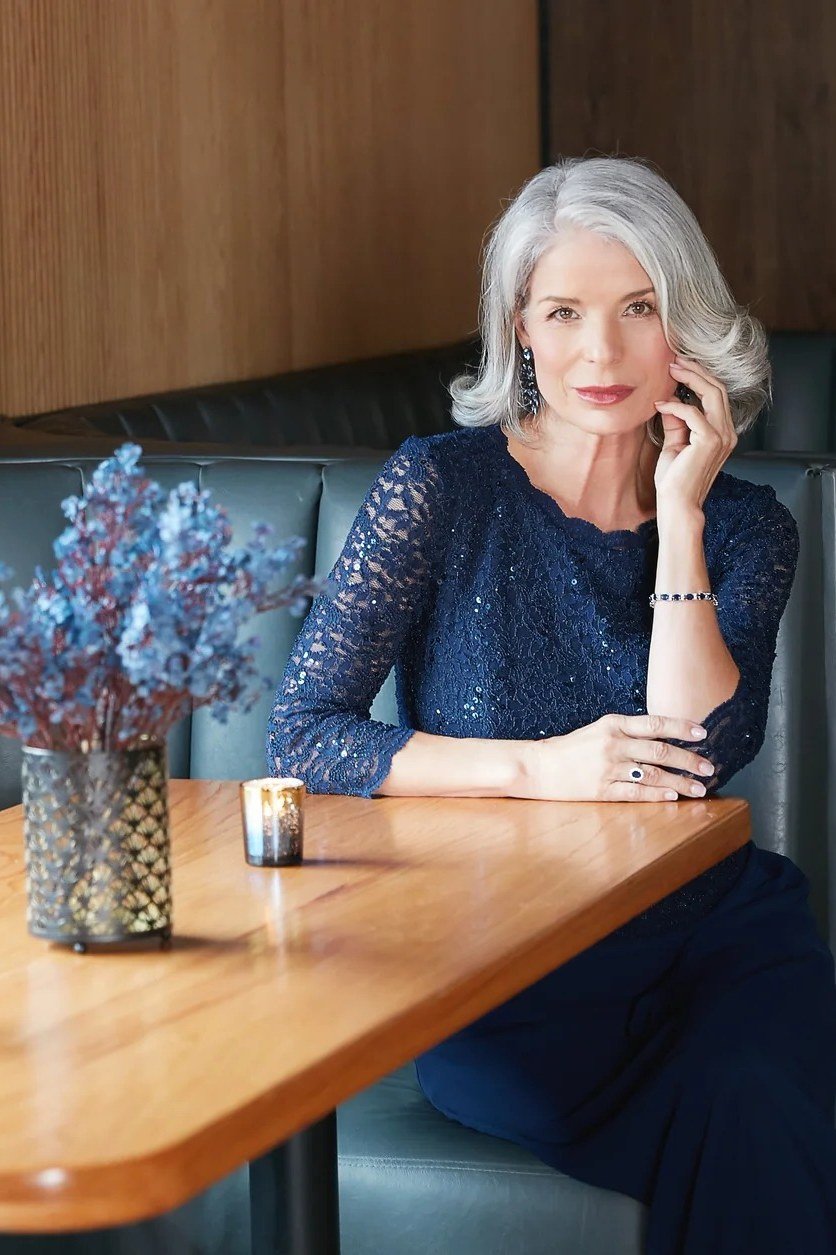 Navy lace dress seated at restaurant table for women over 50, fall date night outfit