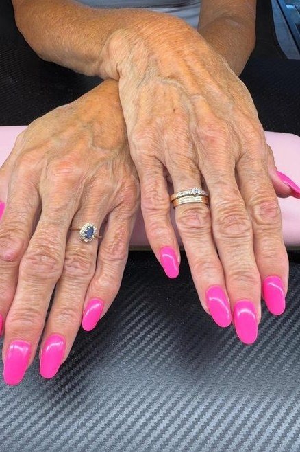 Hot pink long nails on elderly hands