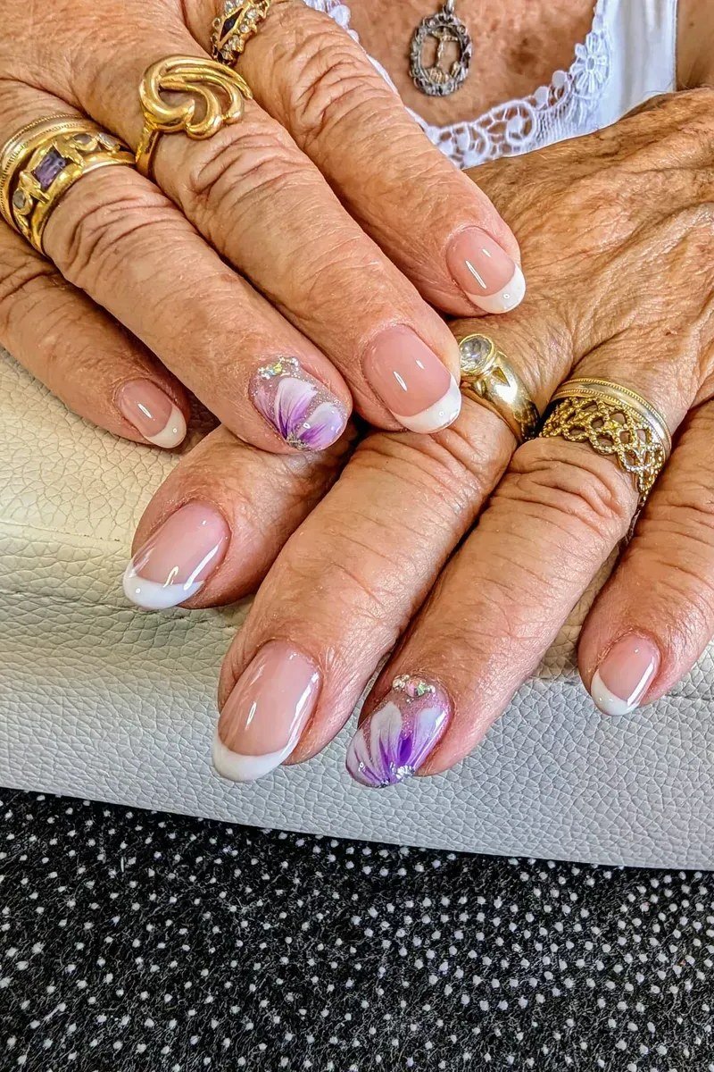 French tip nails with purple floral art on mature hands