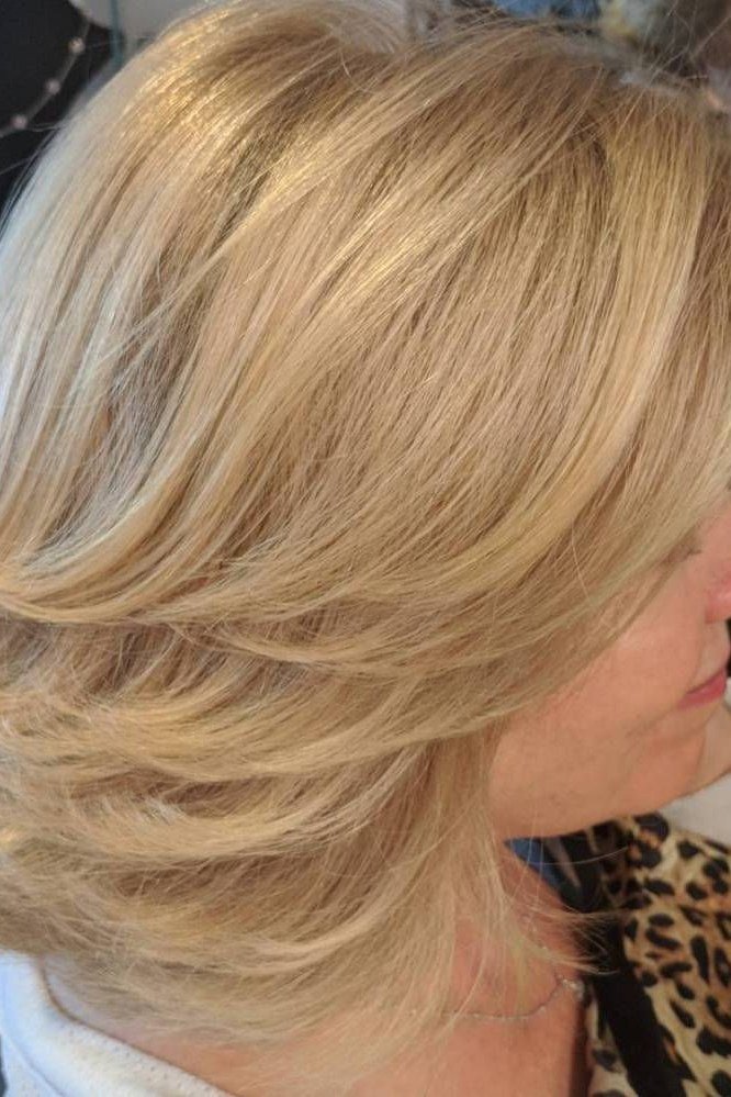 Golden-blonde smooth layered medium-length hairstyle, side view, for women over 50