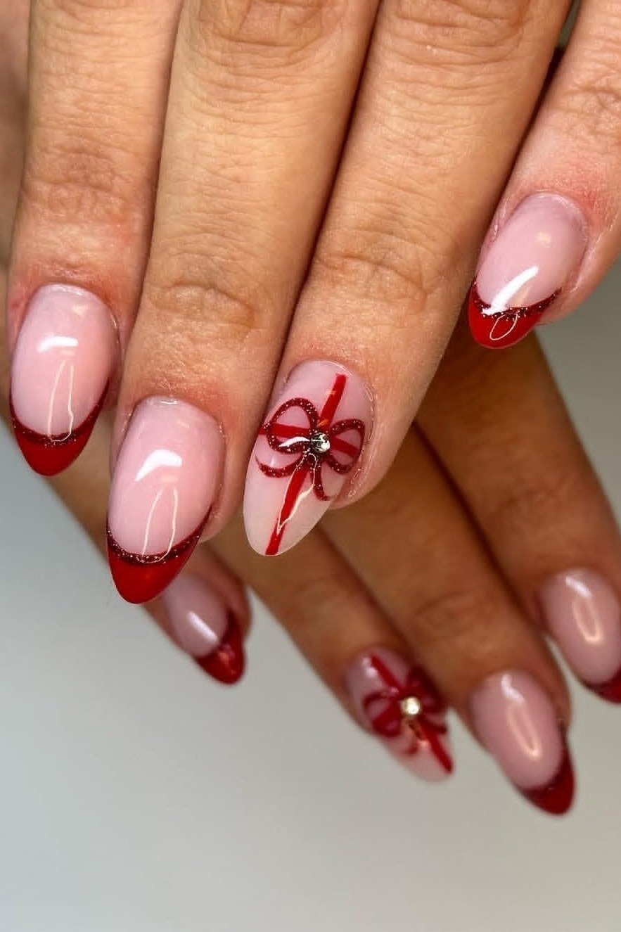 nude nails with red french tips and gift bow accent