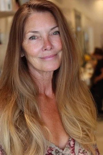 Long honey-blonde wavy hair with center part for women over 50