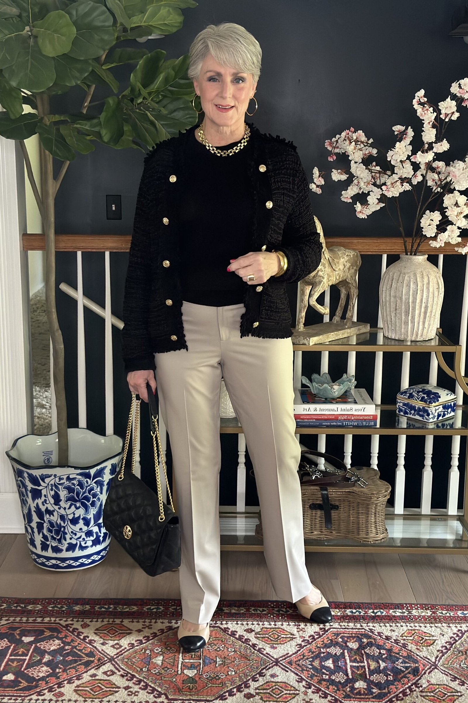 Effortlessly chic fall outfit for women over 60: black cardigan with gold buttons over cream trousers