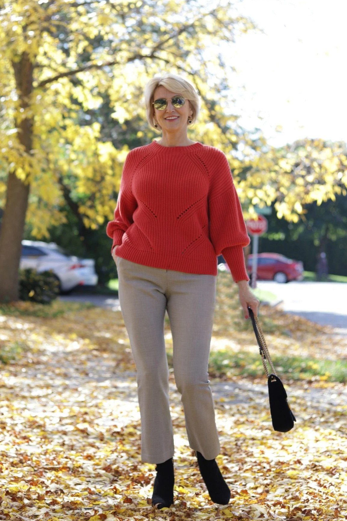 Red knit sweater with beige trousers and black ankle boots, bold weekend outfit for women over 40
