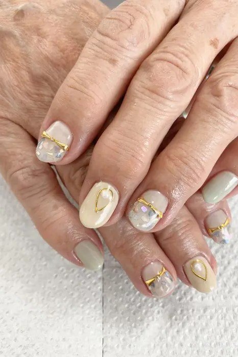Sage green gel nails with gold for mature hands