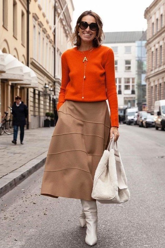 Fall city outfit for women over 50: orange cardigan camel midi skirt white boots white bag