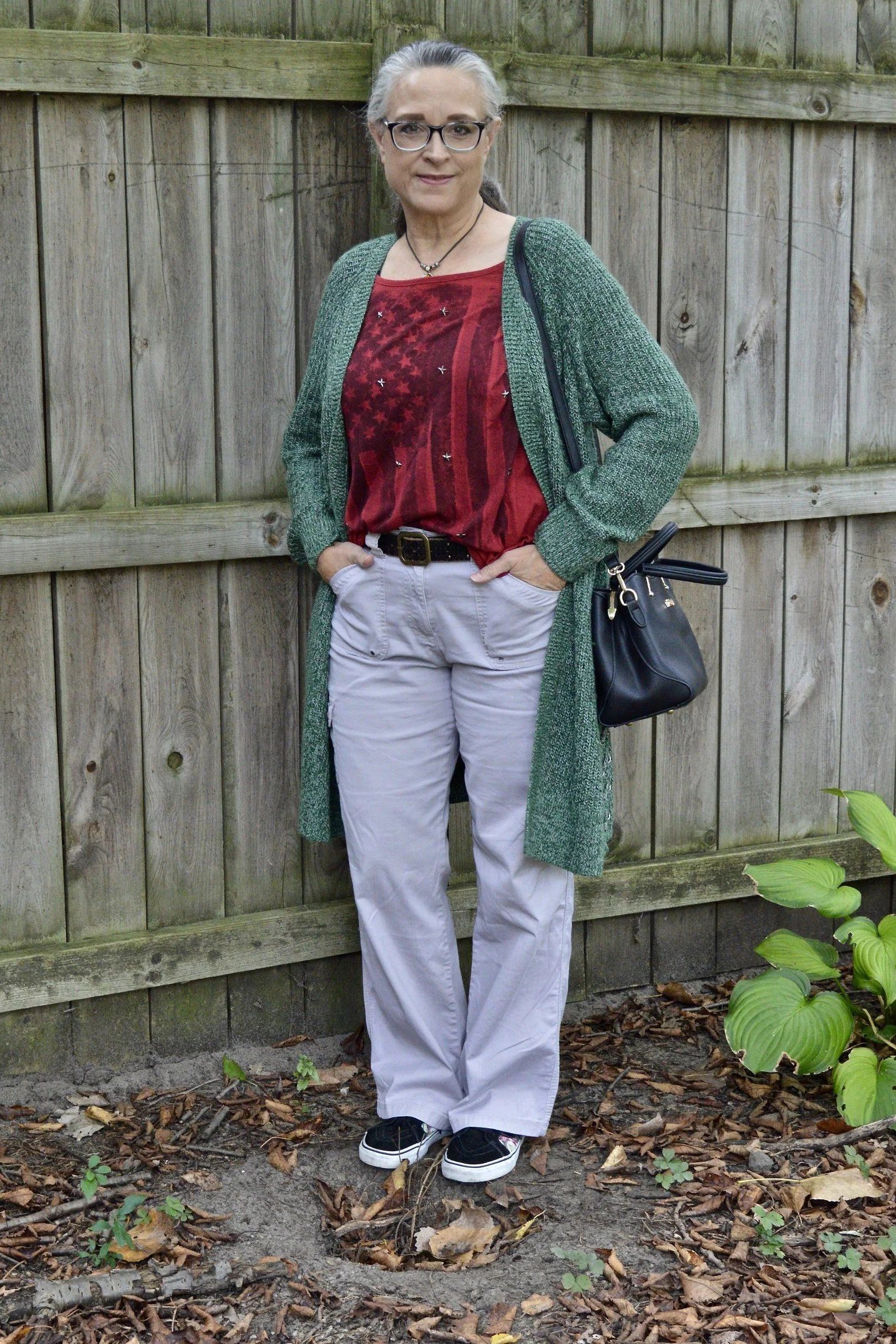 Woman over 50 wearing green cardigan with red top and grey pants, everyday casual outfit idea