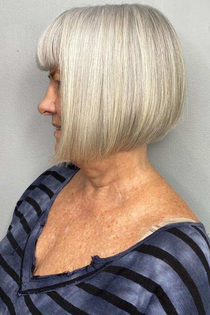Rounded silver-white bob with bangs on an older woman, side profile, medium hairstyle for women over 60