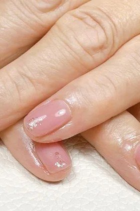 Sheer pink gel nails with gold glitter accent