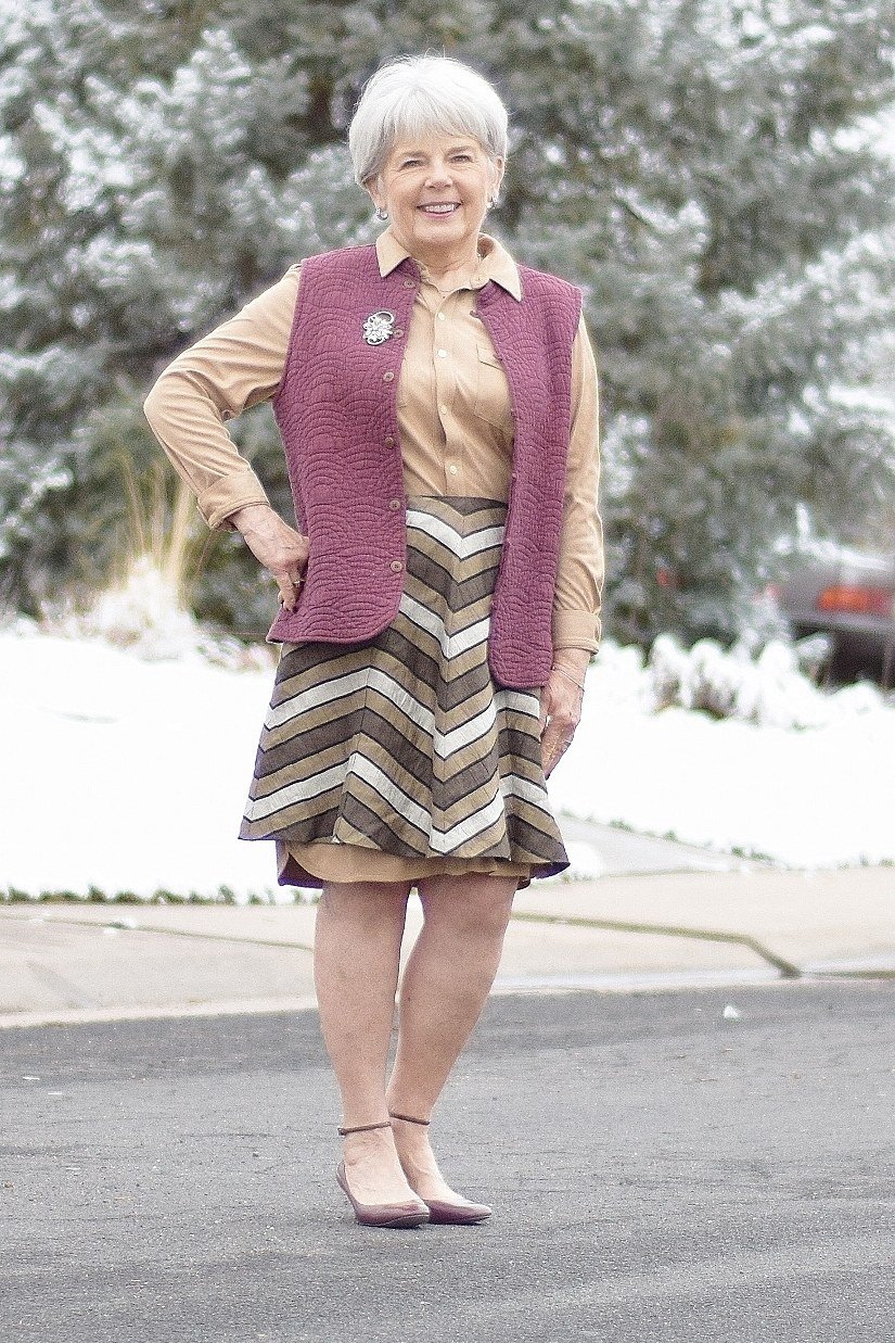 Stylish winter outfit for women over 60: mauve vest with chevron midi skirt in snow