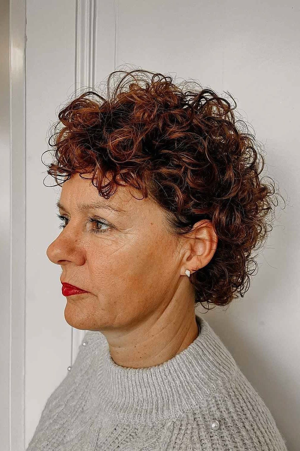 Dark brown tight curly bixie haircut side view for women over 60