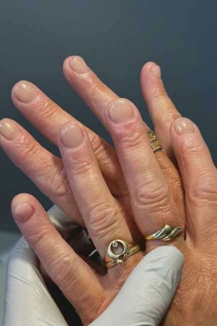 Nude almond glossy nails on elderly hands for women over 70
