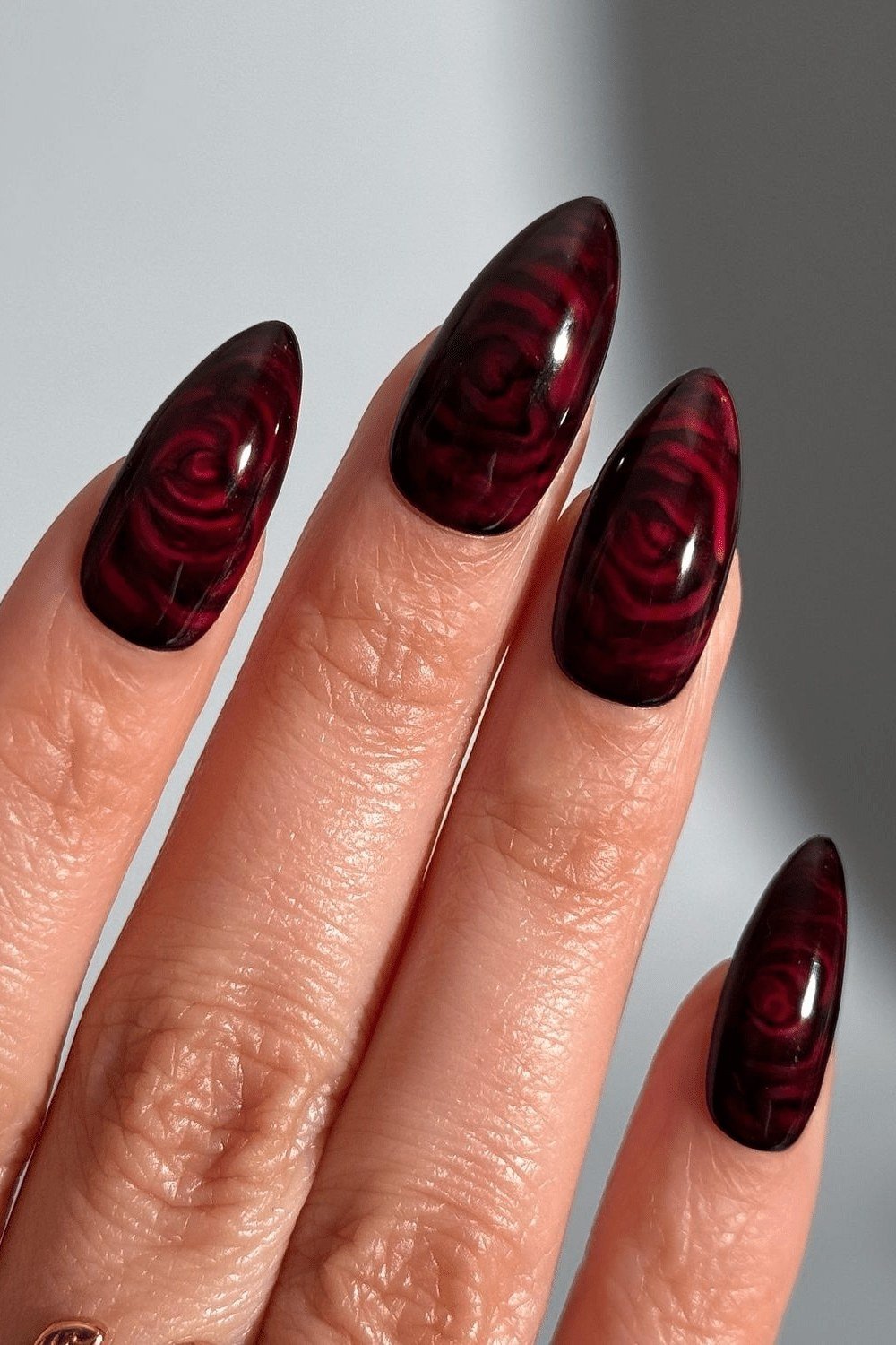 Dark burgundy nails with rose swirl art for women over 50