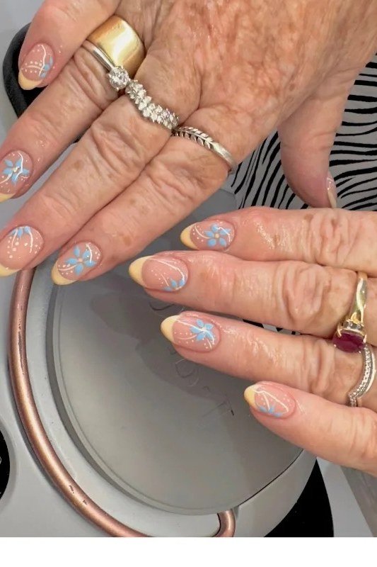 Sheer nails with pale blue dot accents on elderly hands