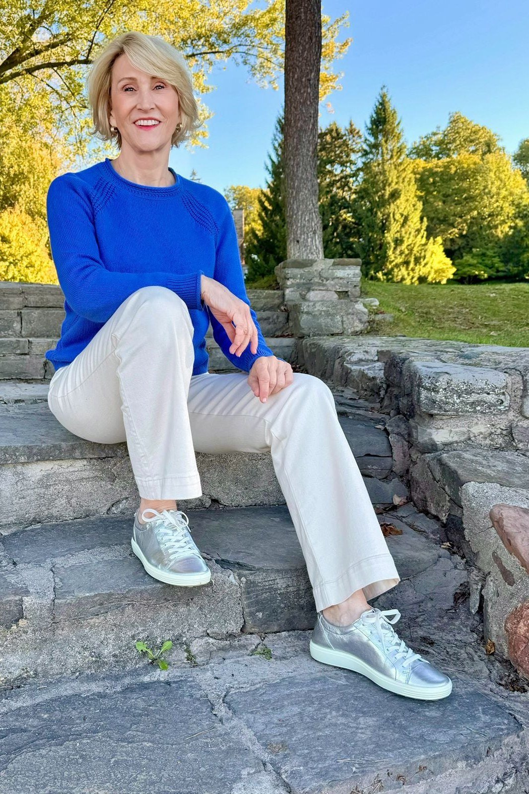 Woman over 50 wearing royal blue sweater with white jeans and sneakers, everyday casual outfit idea