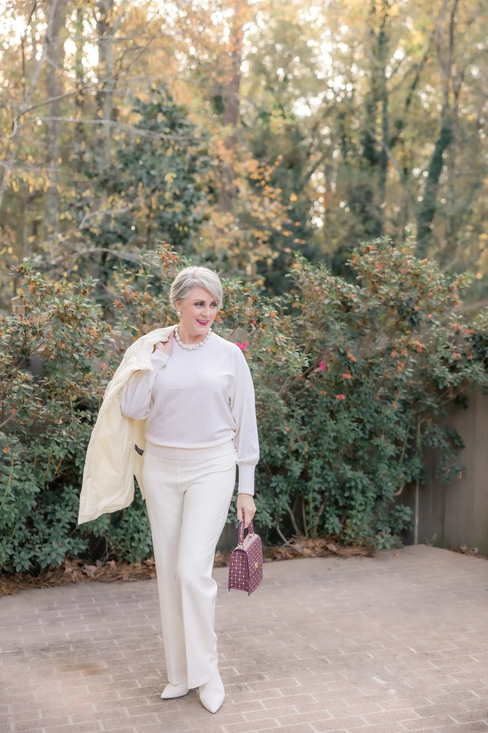 Effortlessly chic fall outfit for women over 60: cream sweater with white trousers and sneakers