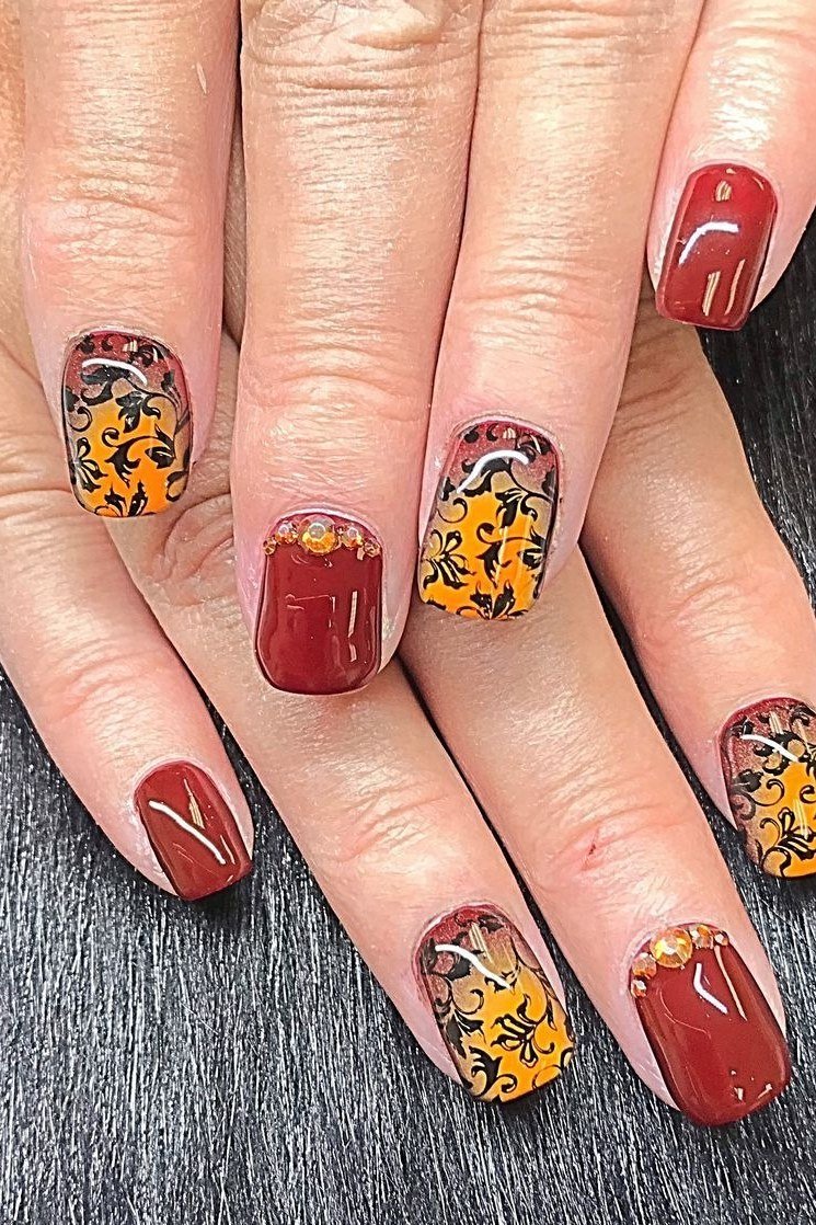 Red nails with leopard and pumpkin art, fall nail design for older women