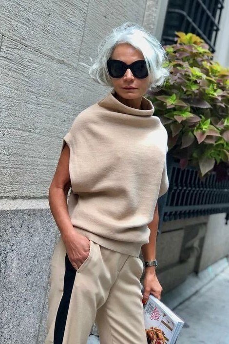 Older woman wearing a beige sleeveless cowl top with beige drawstring trousers