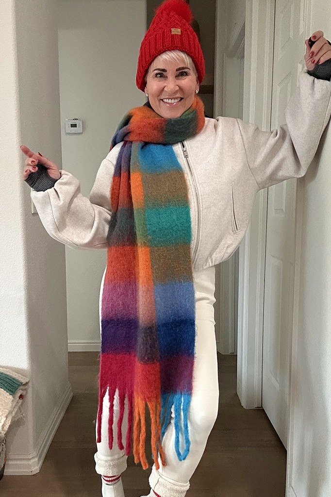 Red beanie with cream puffer jacket, rainbow striped scarf and white jeans
