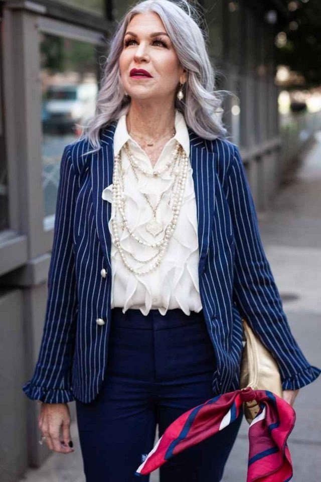 Pinstripe blazer with white ruffle shirt navy trousers and red scarf