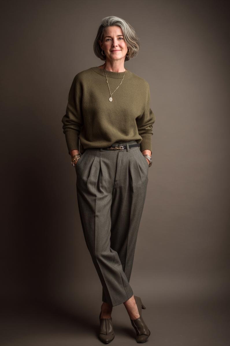 Olive-green sweater tucked into gray pleated trousers for women over 50