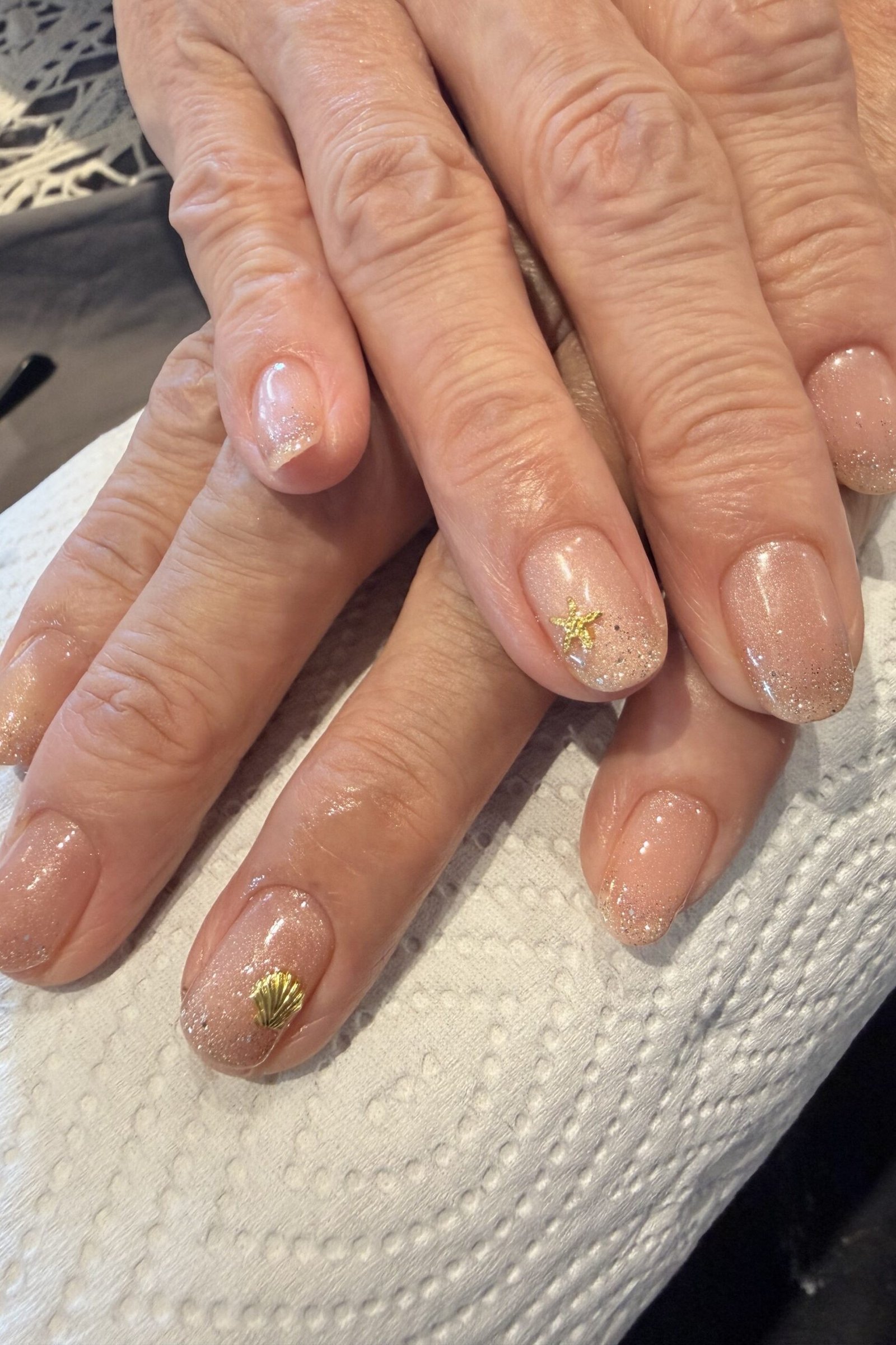 Gold Starflake Accent Nude Nails - gold starflake accent nude mature hands, glitter winter nail design for women over 60