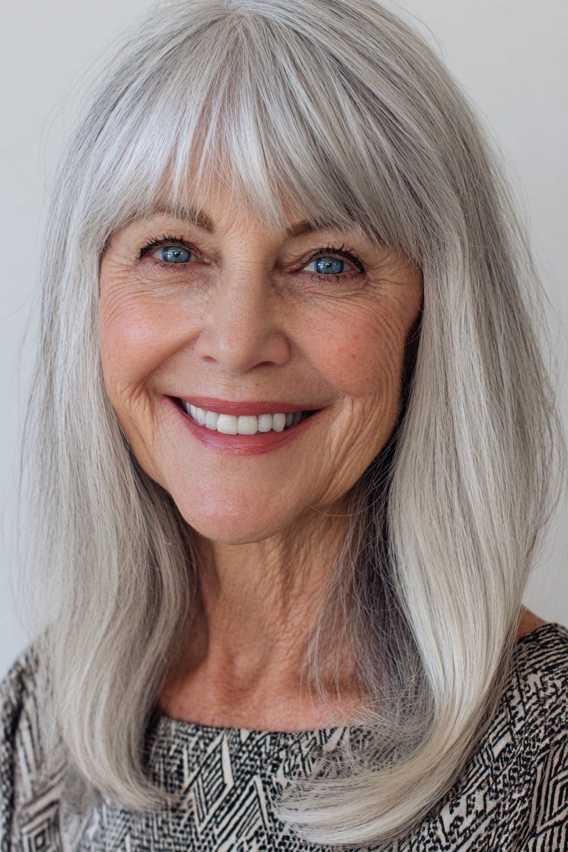 Straight silver-gray shoulder-length hair with bangs on an older woman, front view, medium hairstyle for women over 60