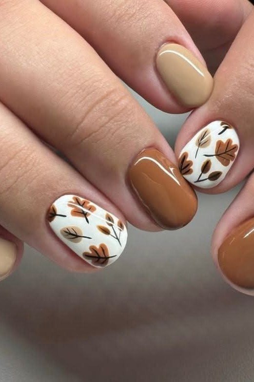 Caramel brown short nails with hand-painted autumn leaf art, glossy warm fall design.
