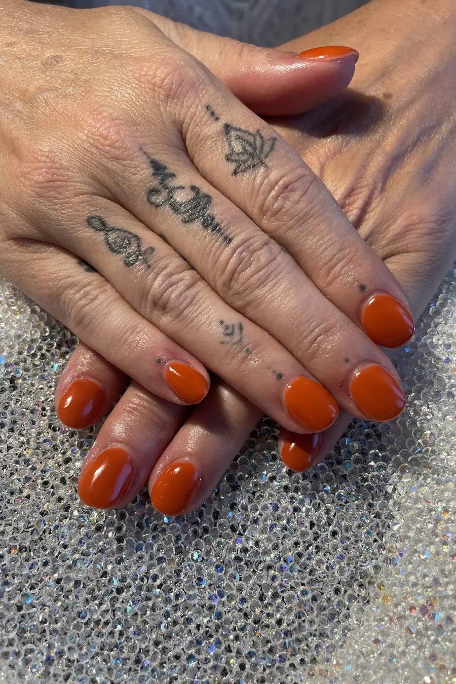Burnt Orange on Tattooed Hands - fall nail color idea for women over 60