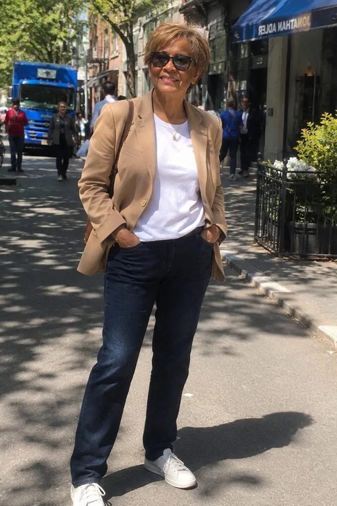 Woman over 50 wearing camel blazer with dark jeans and sneakers, everyday casual outfit idea