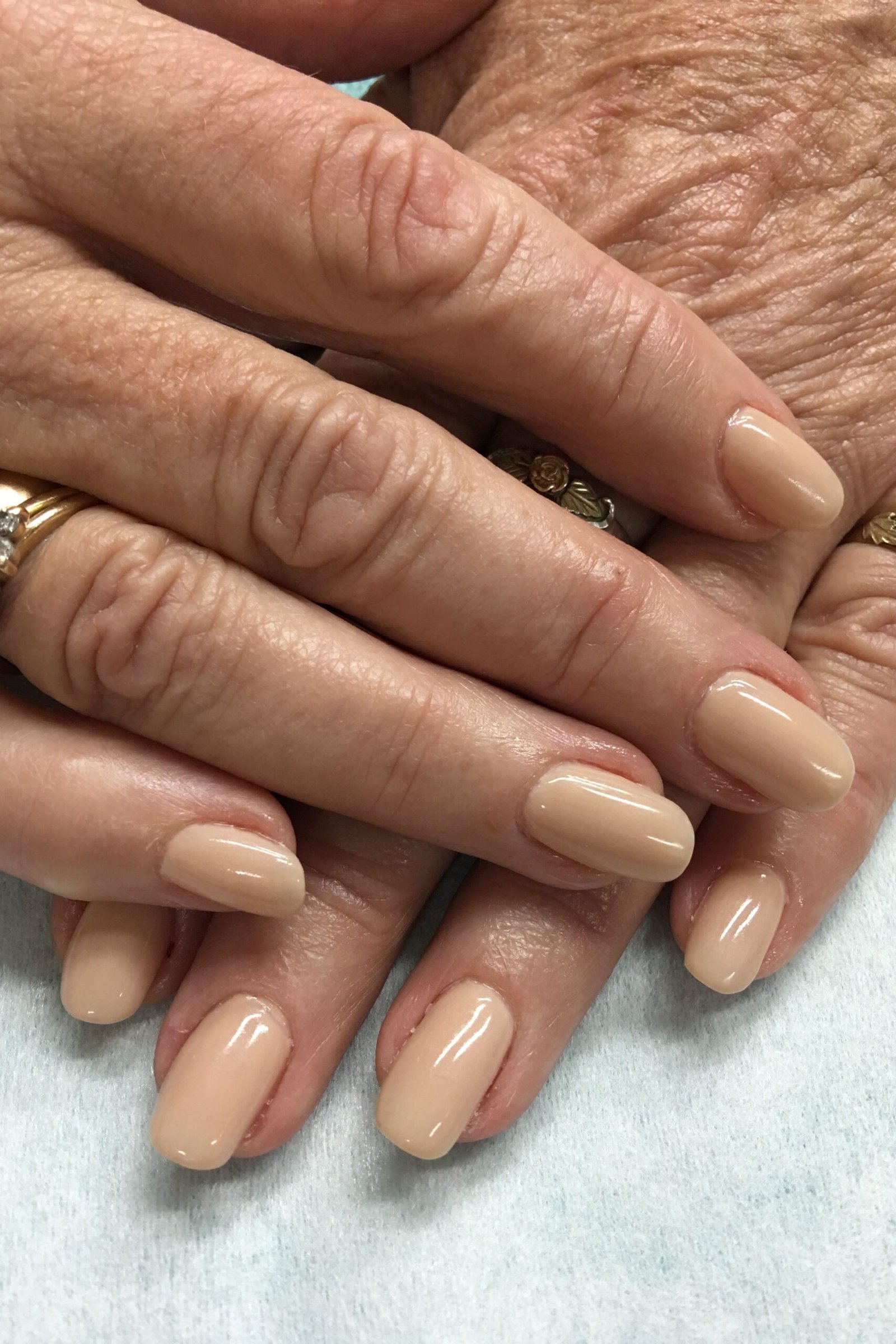 Beige nude nail polish on older hands
