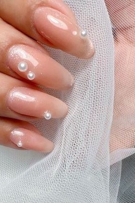 Nude nails with single pearl drop accents