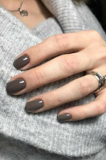 Dark taupe nails with rings on grey knit, sophisticated nail design for women over 50
