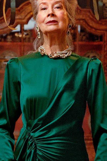 holiday evening outfit for women over 60: emerald satin dress by christmas tree