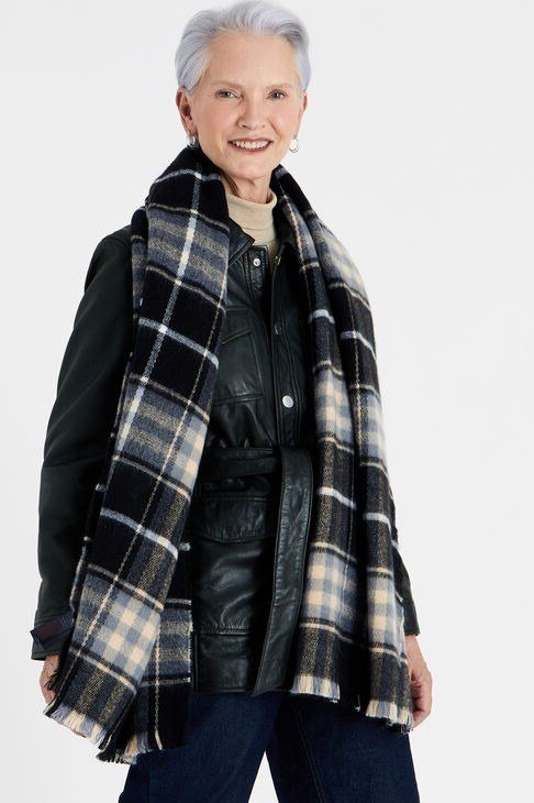 older woman in black leather jacket with black-and-white plaid scarf and jeans, studio