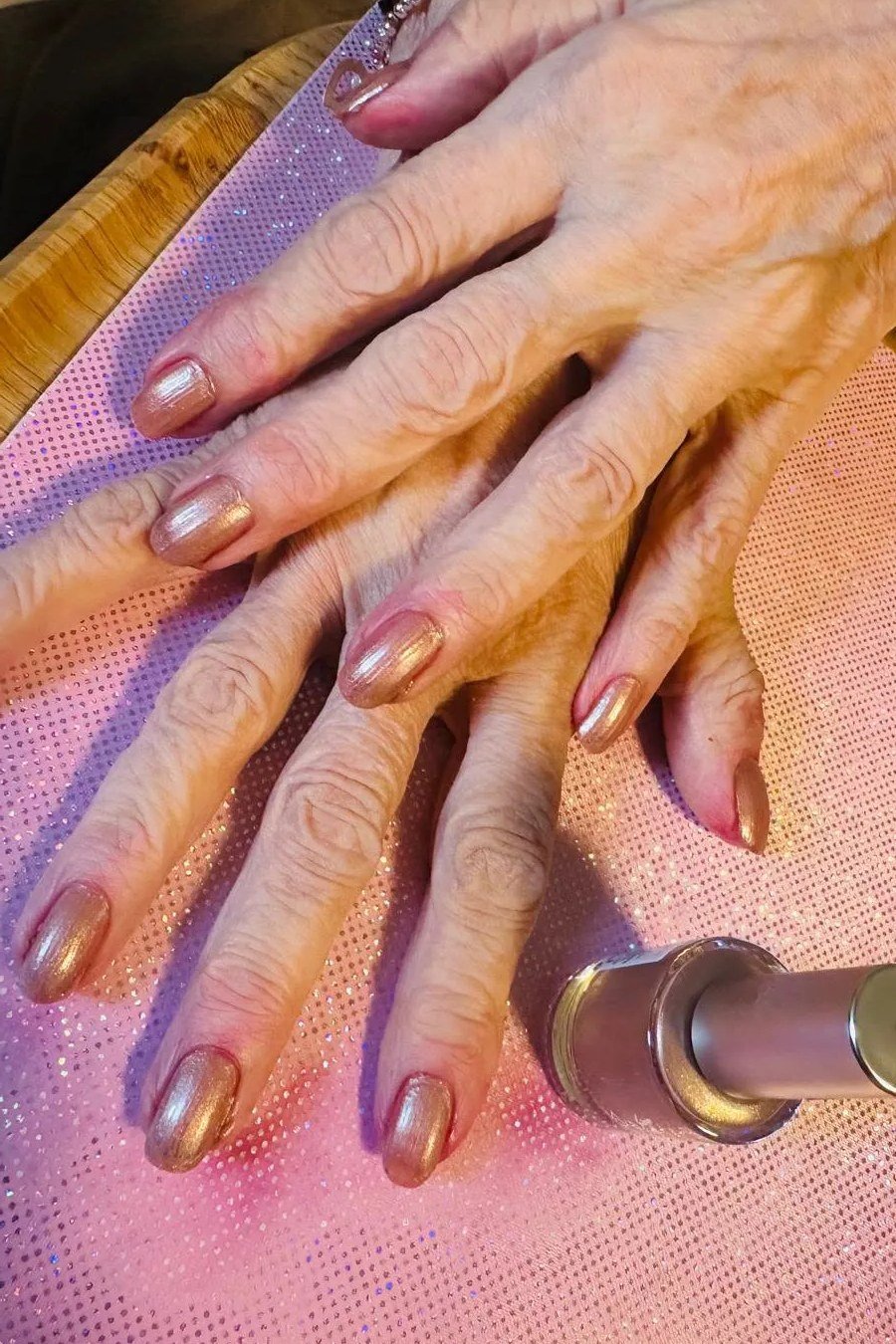 Rose gold chrome nail polish on older hands
