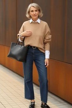 Casual fall outfit for women over 60: white sneakers, camel tote bag, grey sweater, jeans
