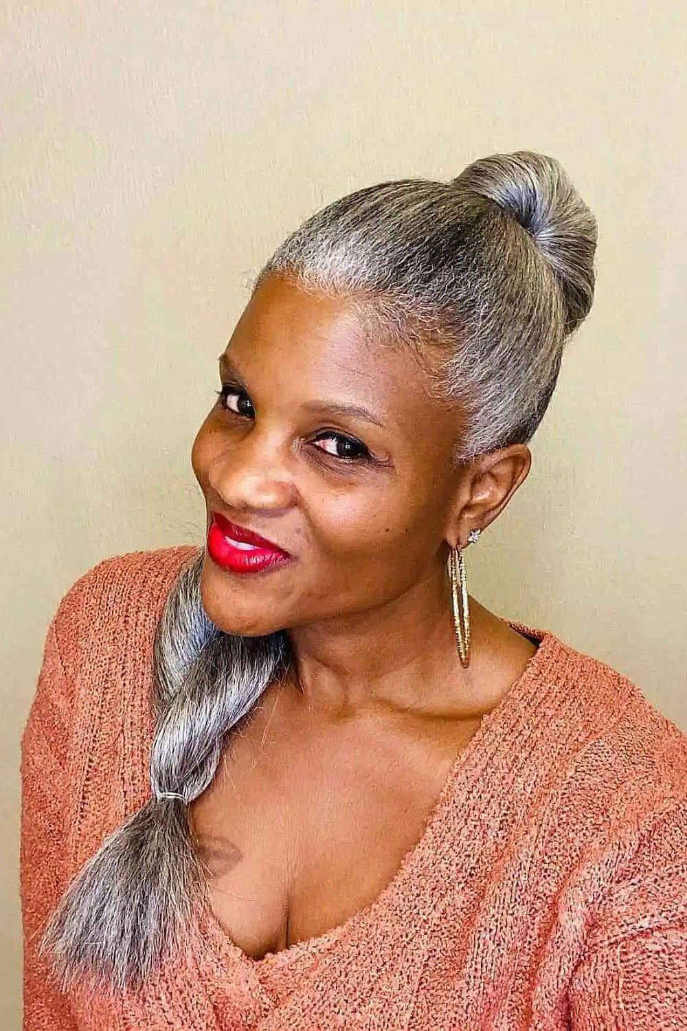 Long gray hair in top bun with side braid for women over 50