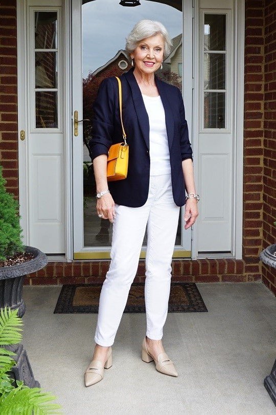 Woman over 50 wearing navy blazer with white jeans and yellow bag, everyday casual outfit idea