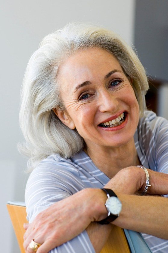 Wavy silver-gray hair on a laughing older woman, front view, medium hairstyle for women over 60