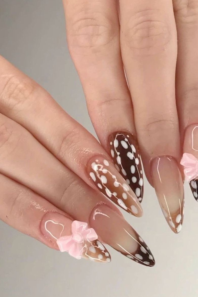 Spotted almond nails with pink bow accents on nude base