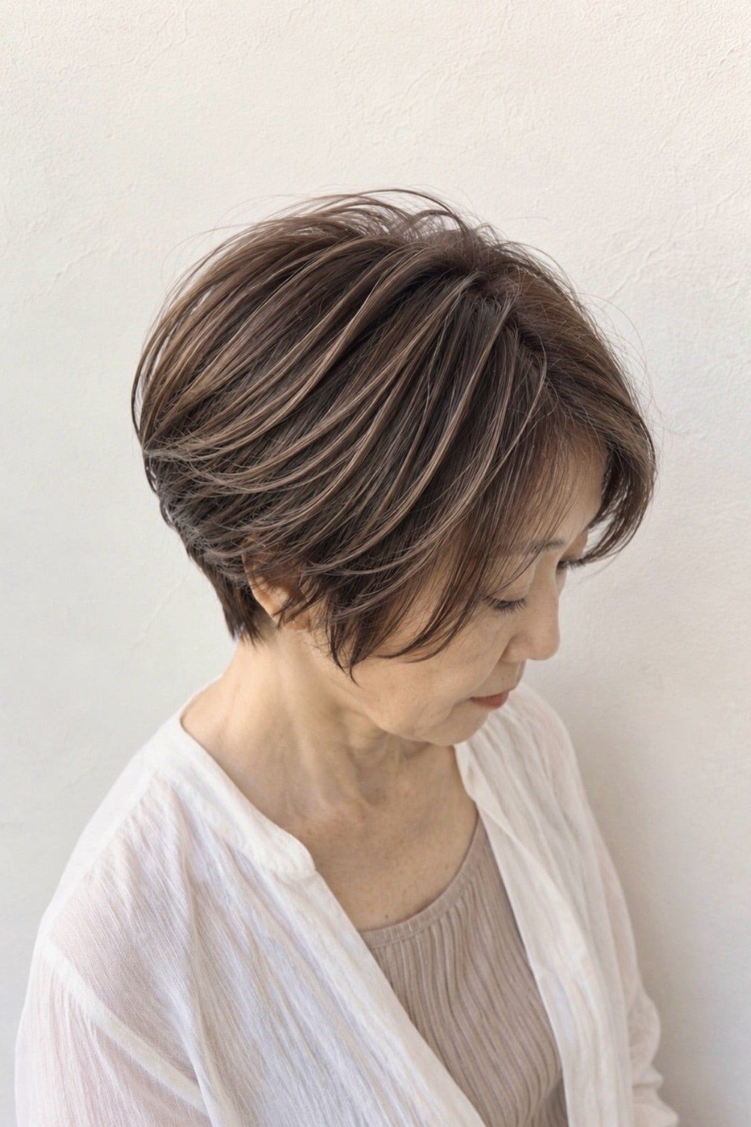 Brunette pixie-bob with side-swept fringe - trendy short haircut for older women with fine hair