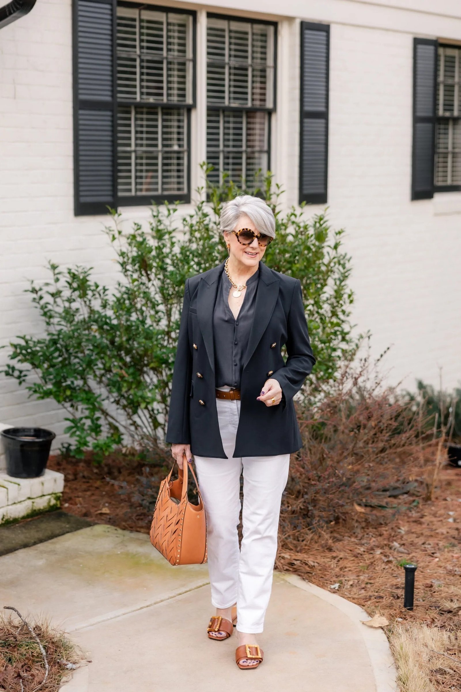 Dark blazer with white jeans and tan bag for women over 60