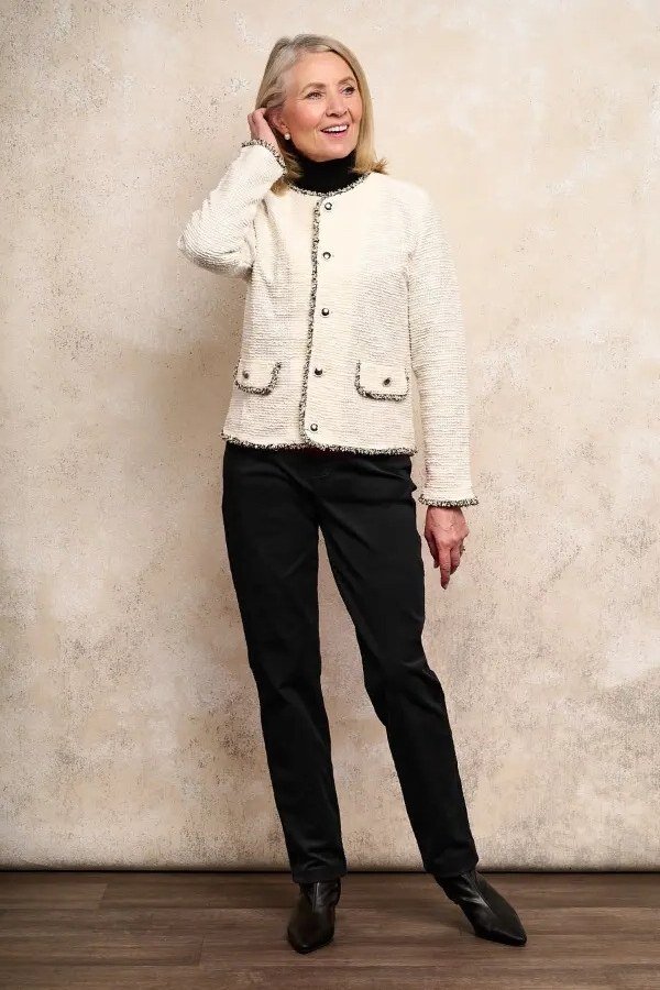 Older woman in white tweed jacket and black slim trousers