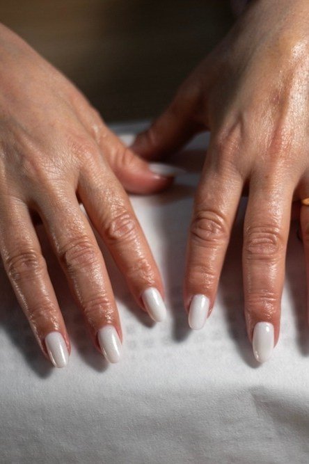 Mature hands with milky white nails in natural daylight