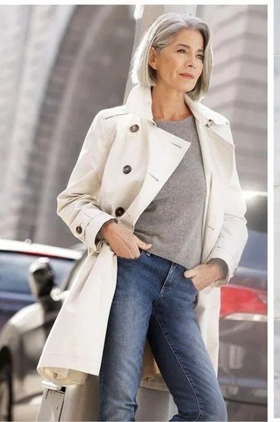 White trench coat over grey top with blue jeans, fresh October outfit for women over 50