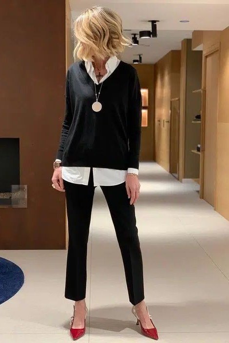 Black sweater over white shirt with black trousers and red heels in a hallway
