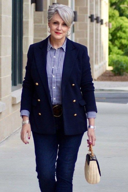 Woman over 50 in a navy blazer with a checked shirt and dark jeans for business casual