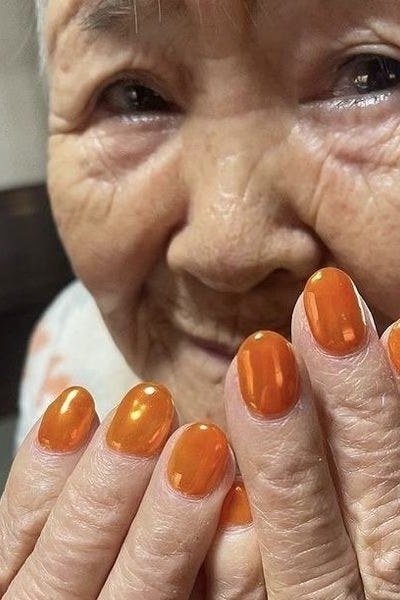 Bright orange nails on smiling elderly woman
